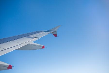 飞机机翼和明亮的天空，通过飞机窗口