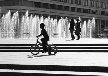 喷泉池边骑自行车的男孩